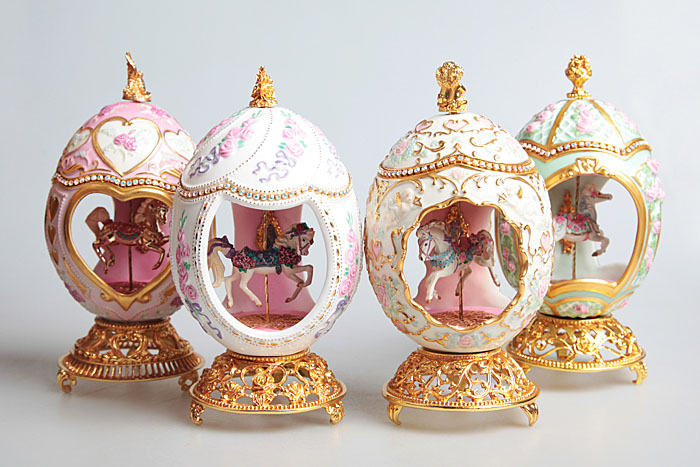 Набор музыкальных яиц Карусель. Фарфор, золочение, металл, стразы. House of Faberge, 1990-е годы ХХ векаАККАА Набор музыкальных яиц Карусель. Фарфор, золочение, металл, стразы. House of Faberge, 1990-е годы ХХ векаАККААНабор музыкальных яиц Карусель. Фарфор, золочение, металл, стразы. Фаберже. Западная Европа, 1990-е годы ХХ века. Размер яйца 17 х 9 см. Размер коробки 36 х 46 х 15 см. Сохранность очень хорошая. На основании яиц вензель Ф, TRM. В тулове каждого яйца сделано три больших окна, обрамленных золотыми рамками. В центре помещена фигурка лошади, подобная тем, которые бывают на карусели. Яйца оформлены букетами цветов: они помещены на тулове между окнами, в верхней части. По кромке навершия идет линия блестящих фианитов. При вращении небольшой золотой ручки вверху играет легкая, приятная мелодия.