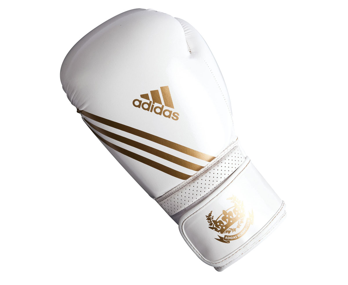 Перчатки боксерские Adidas Hybrid Aero Tech, цвет: бело-золотой. adiBL06. Вес 8 унцийadiBL06 Перчатки боксерские Adidas Hybrid Aero Tech, цвет: бело-золотой. adiBL06. Вес 8 унцийadiBL06Боксерские перчатки Adidas Hybrid Aero Tech изготовлены из полиуретана PU4G, который по своим качествам не уступает натуральной коже. Внутренний наполнитель из многослойной пены закрывает тыльную сторону и боковую часть ладони, обеспечивая надежную защиту рук боксера и позволяя безопасно тренироваться в полную силу. Загнутый параллельно кулаку большой палец обеспечивает безопасность при нанесении ударов и защищает большой палец от вывихов и травм. Вентиляционные отверстия на ладони создают максимальный уровень комфорта для рук, поддерживая оптимальный микроклимат внутри перчаток. Широкий ремень, охватывая запястье, полностью оборачивается вокруг манжеты, благодаря чему создается дополнительная защита лучезапястного сустава от травмирования. Застежка на липучке способствует быстрому и удобному одеванию перчаток, плотно фиксирует перчатки на руке.