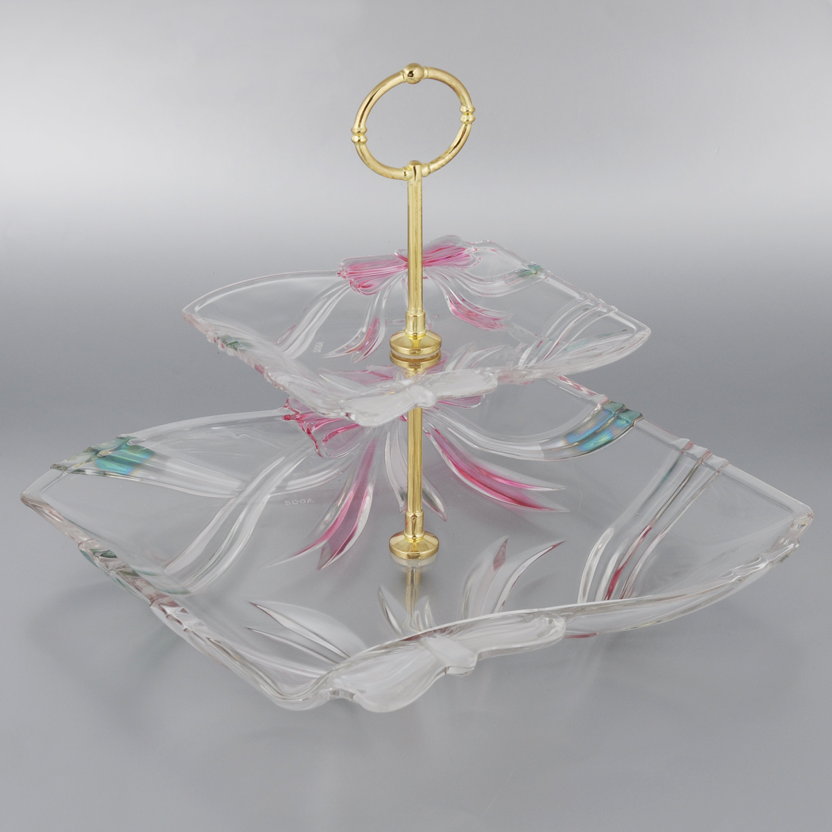 Фруктовница Soga Ribbon, двухъяруснаяA42855Z Фруктовница Soga Ribbon, двухъяруснаяA42855ZДвухъярусная фруктовница Soga Ribbon выполнена из высококачественного стекла в виде двух блюд на изящной ножке и оснащена ручкой для удобной переноски. Изделие имеет многогранную рельефную поверхность в форме бантов и имеет изысканный внешний вид. Фруктовница Soga Ribbon станет идеальным украшением любой кухни или прекрасным подарком для вас и ваших близких. Размер большого блюда (по верхнему краю): 29,5 х 29,5 см. Размер малого блюда (по верхнему краю): 17 х 17 см. Общая высота фруктовницы (в собранном виде): 26 см.